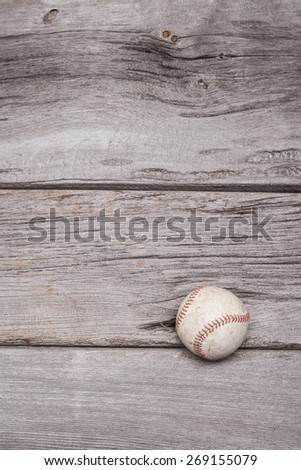 A worn baseball sits on a rustic wooden background. The photograph was shot in portrait format but could be rotated into landscape.