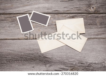 Some vintage photographs and envelopes sit on top of a rustic wooden table top. The frames are blank and can easily be filled with your photographs.