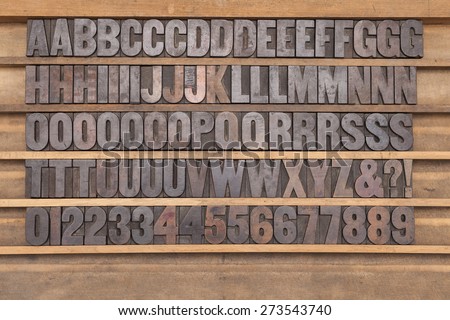 A full set of wooden letterpress type in a printers drawer. Some characters are more ink stained than others due to usage patterns.