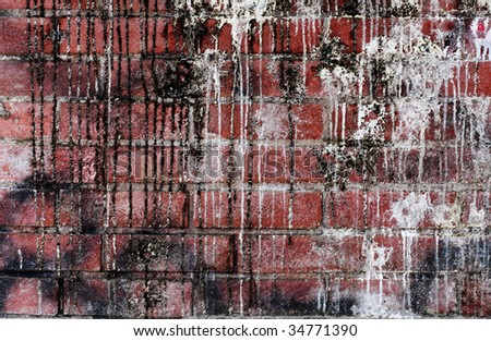 Red brick wall covered in white and black paintball splatters.