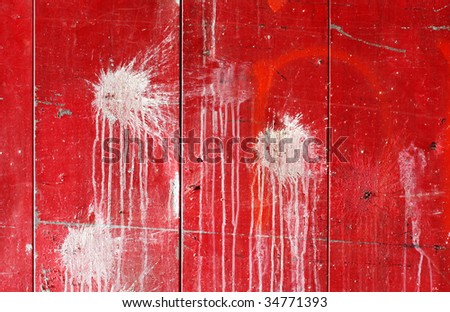 Red industrial door covered in white paintball splatters.