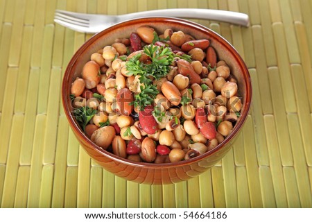 A delicious bowl of bean salad on a green bamboo placemat.