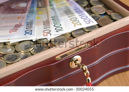 View in a partly open treasure chest full of euro coins and banknotes