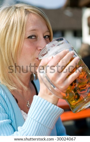 Young beautiful Woman drinks beer out of a bavarian beer stein at the oktoberfest