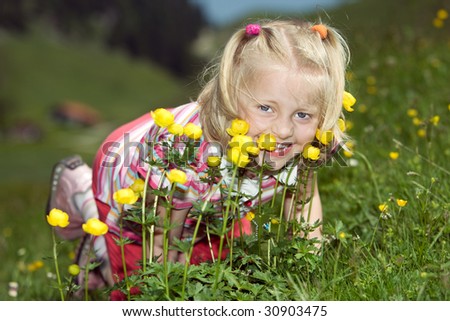Young child on a meadow with flowers smiles into camera