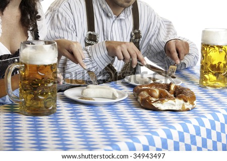 close-up of Bavarian couple having lunch at Oktoberfest with beer stein (Mass), Sausage (Weisswurst) and Pretzel (Brezn)