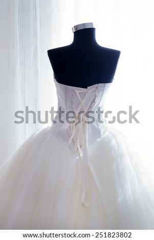 wearing a wedding dress on a mannequin, stands in front of the window