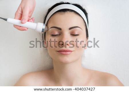 beautiful woman getting ultrasound skin cleaning and face treatment at beauty salon cosmetologist takes care of her face