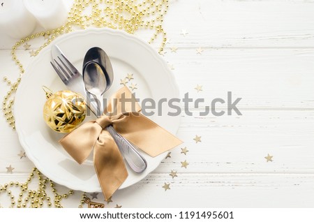 Festive place setting for christmas dinner on white rustic background. Christmas table setting with gold decorations on wooden table. Holiday Decorations. Top view. Copy space.