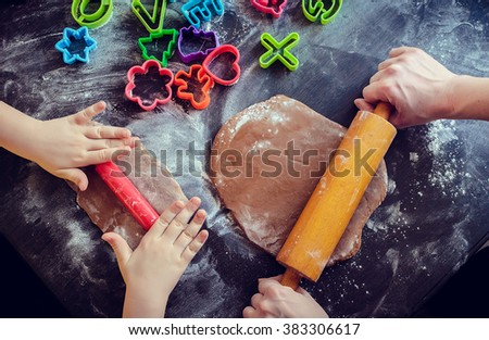 Hands of mother and daughter using rolling pins together in the kitchen. Mother teaching daughter how to bake cookies for holidays. Easter baking preparation. Easter food concept. Top view.