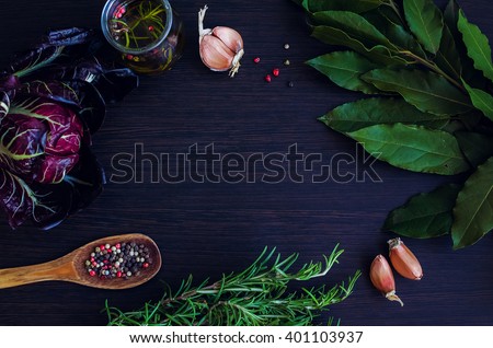 Rosemary, garlic, chicory, Bay leaf, olive oil with spices, wooden spoon with pepper on dark background. Background layout with free text space. Copy space. Top view. Food flat lay.