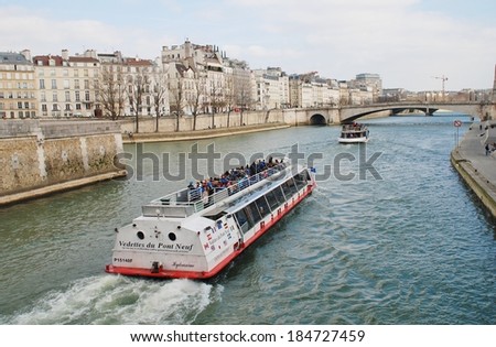 PARIS, FRANCE - MARCH 18, 2014: Excursion boats head towards the Pont De La Tournelle on the River Seine. Numerous such boats ply the Seine each day, passing many famous Paris landmarks.