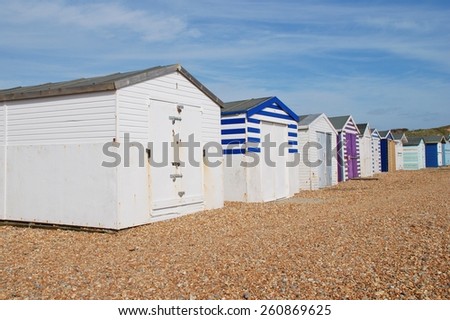 A row of traditional British beach huts on the pebble beach at Glyne Gap between Hastings and Bexhill-on-Sea in East Sussex, England.