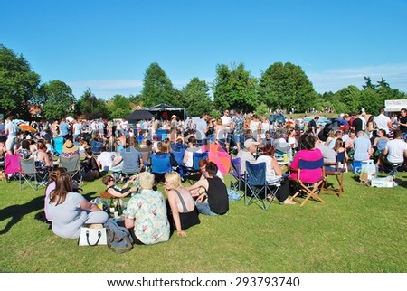 TENTERDEN, ENGLAND - JULY 4, 2015: The audience sit on the grass in the local park at the annual free Tentertainment music festival. The community event was first held in 2008.