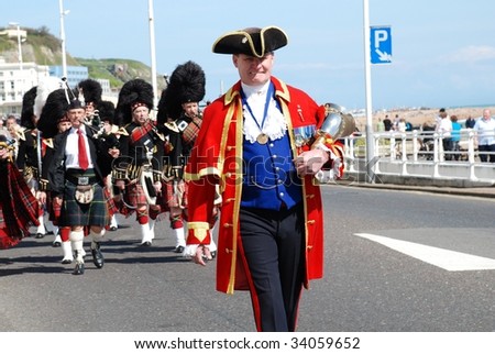 HASTINGS, ENGLAND-APRIL 26: John Bartholomew, Town Crier, leads the 1066 Pipes and Drums Band on a St.George\'s Day parade on April 26, 2009 along the seafront at Hastings, East Sussex.