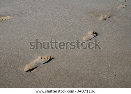 A line of human footprints in the sand on the beach at Folkestone in Kent, England.