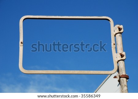 A blank rectangular advertising sign framing a blue sky background.