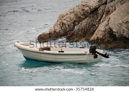 Small power boat moored off the rocky coastline at Brela in Croatia.