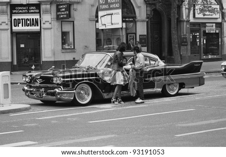 LONDON - MAY 15: Music fans admire a vintage American car during the Rock \'n\' Roll Radio Campaign march on May 15, 1976 in London, England. The campaign aims to get more Rock \'n\' Roll music played on radio.