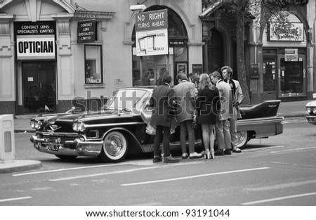 LONDON - MAY 15: Music fans admire a vintage American car during  the Rock \'n\' Roll Radio Campaign march on May 15, 1976 in London, England. The campaign aims to get more Rock \'n\' Roll music played on radio.