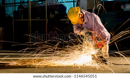 worker uses grinding cut metal, focus on flash light line of sharp spark,in low light