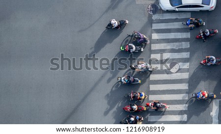 Top view aerial photo of motorcycle driving pass pedestrian crosswalk in traffic road with light and shadow silhouette