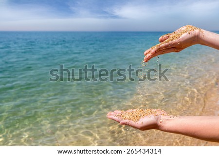 Hands pouring coral sand on the sea background