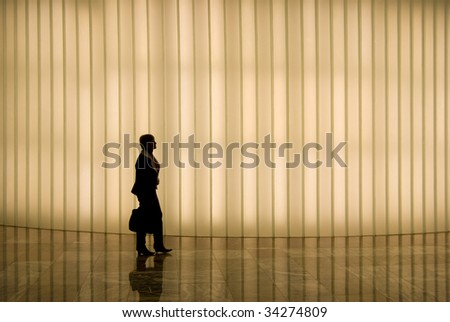 silhouette of business woman walking in front of lighted wall