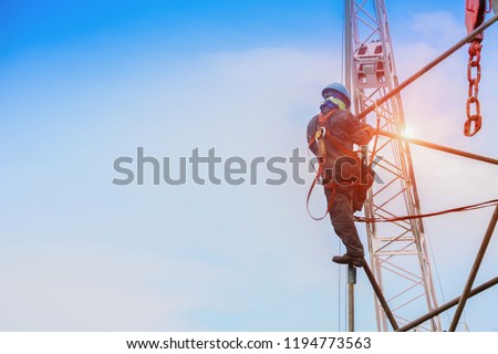Construction worker wearing safety harness and safety line working on high with scaffolding with equipment protective on crane background
