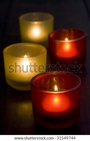 Four candles, the first in focus, others blurred
