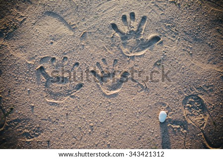 The family left hand prints on the sand on the beach
