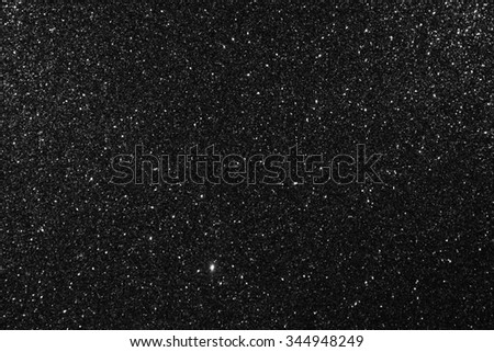 Glittering black background. Twinkling glitter particles.