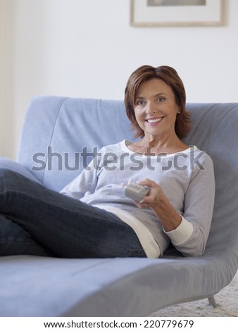 Relaxed portrait of mature woman sitting in a reclining chair holding a TV remote