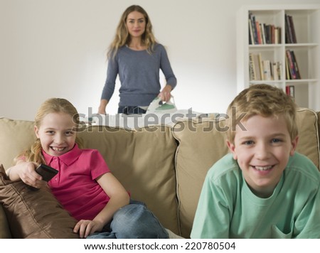 Domestic scene with mother ironing and children watching television