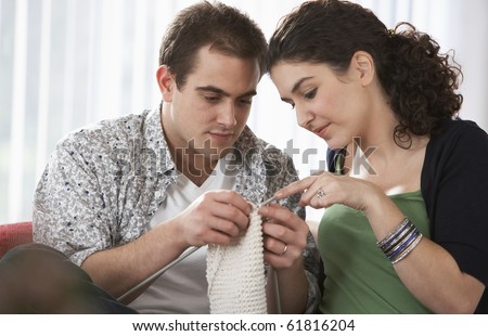 Young woman teaches a young man to knit in a domestic setting