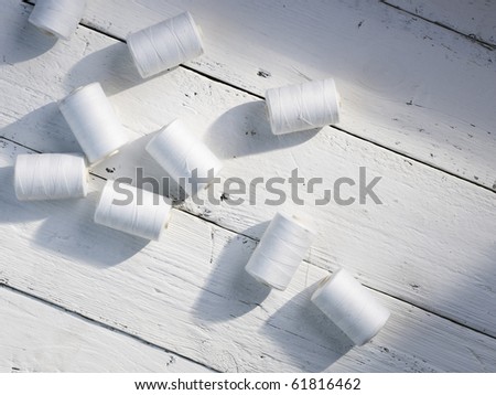 several white cotton reels in the sunlight on a rough white wooden table