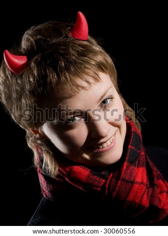 A young  smiling sexual girl in an image of a devil  in red and black with   horns on her head posing on a dark  background