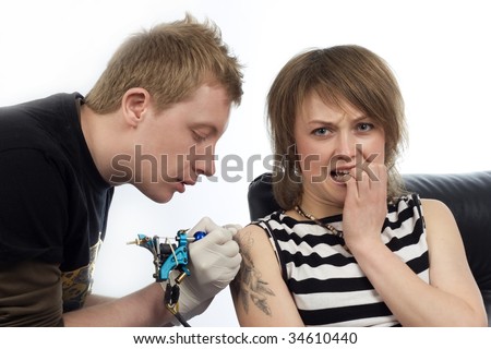 A man drawing tattoo pictures on frightened woman arm