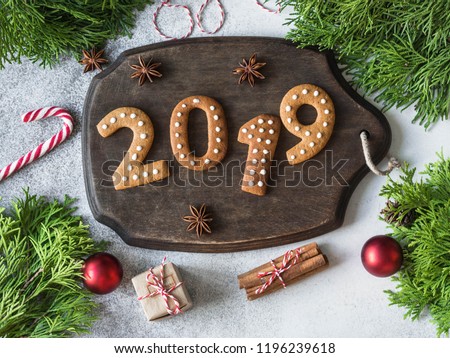 Ginger Christmas or New Year cookies in the form of numbers 2019 on a dark wood board on gray background. top view. Seasonal packaging and New Year\'s attributes