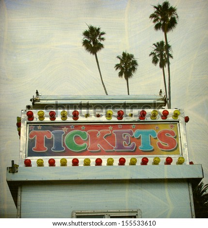aged and worn vintage photo of carnival ticket booth and palm trees