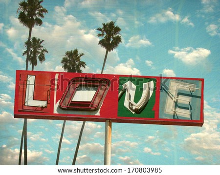 aged and worn vintage photo of neon love sign with palm trees