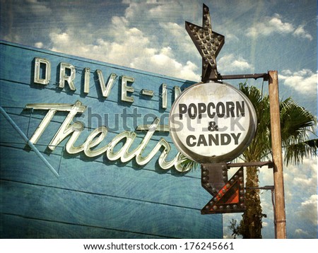 aged and worn vintage photo of drive in movies sign with popcorn and candy advertisement