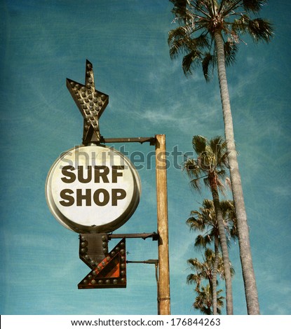 aged and worn vintage photo of surf shop sign on beach with palm trees