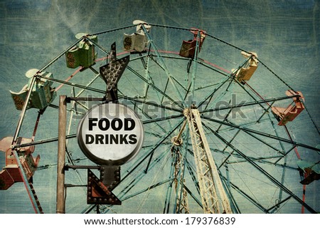 aged and worn vintage photo of food and drinks sign at carnival with ferris wheel