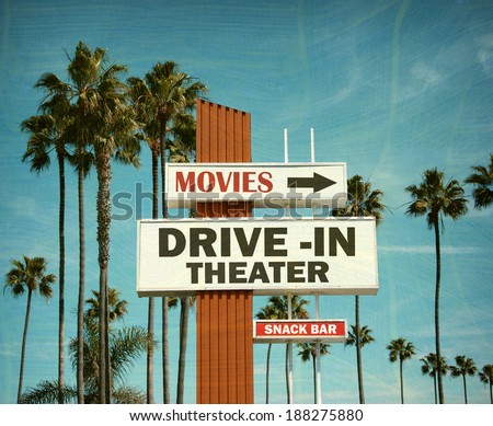 aged and worn vintage photo of drive in theater sign with pal trees