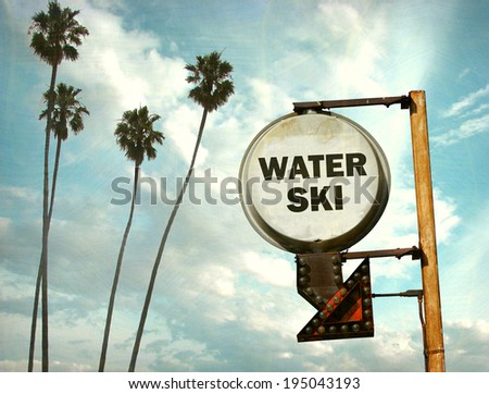 aged and worn vintage photo of water ski sign with palm trees