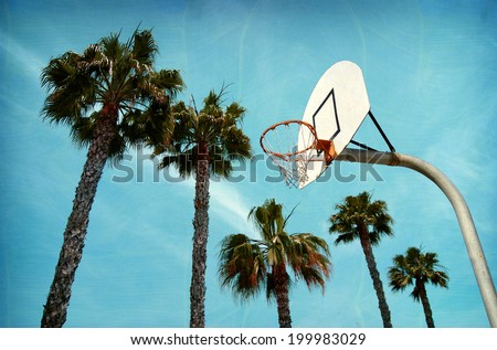 aged and worn vintage photo of outdoor basketball hoop at beach with palm trees
