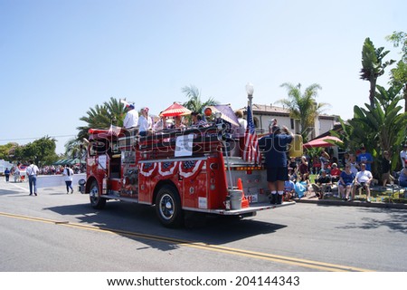 HUNTINGTON BEACH, CA - JULY 4: Fire truck with people riding on top and waving during Huntington Beach July 4th parade.