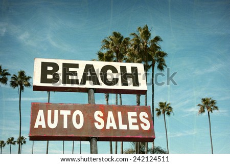 aged and worn vintage photo of auto sales sign on beach