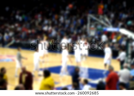blurred background of basketball crowd watching players practice before game